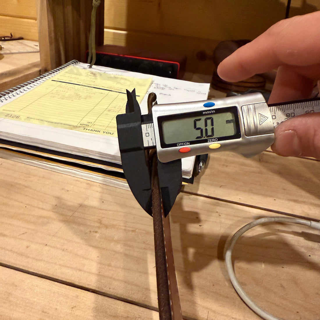 mens leather belt getting measured with calipers